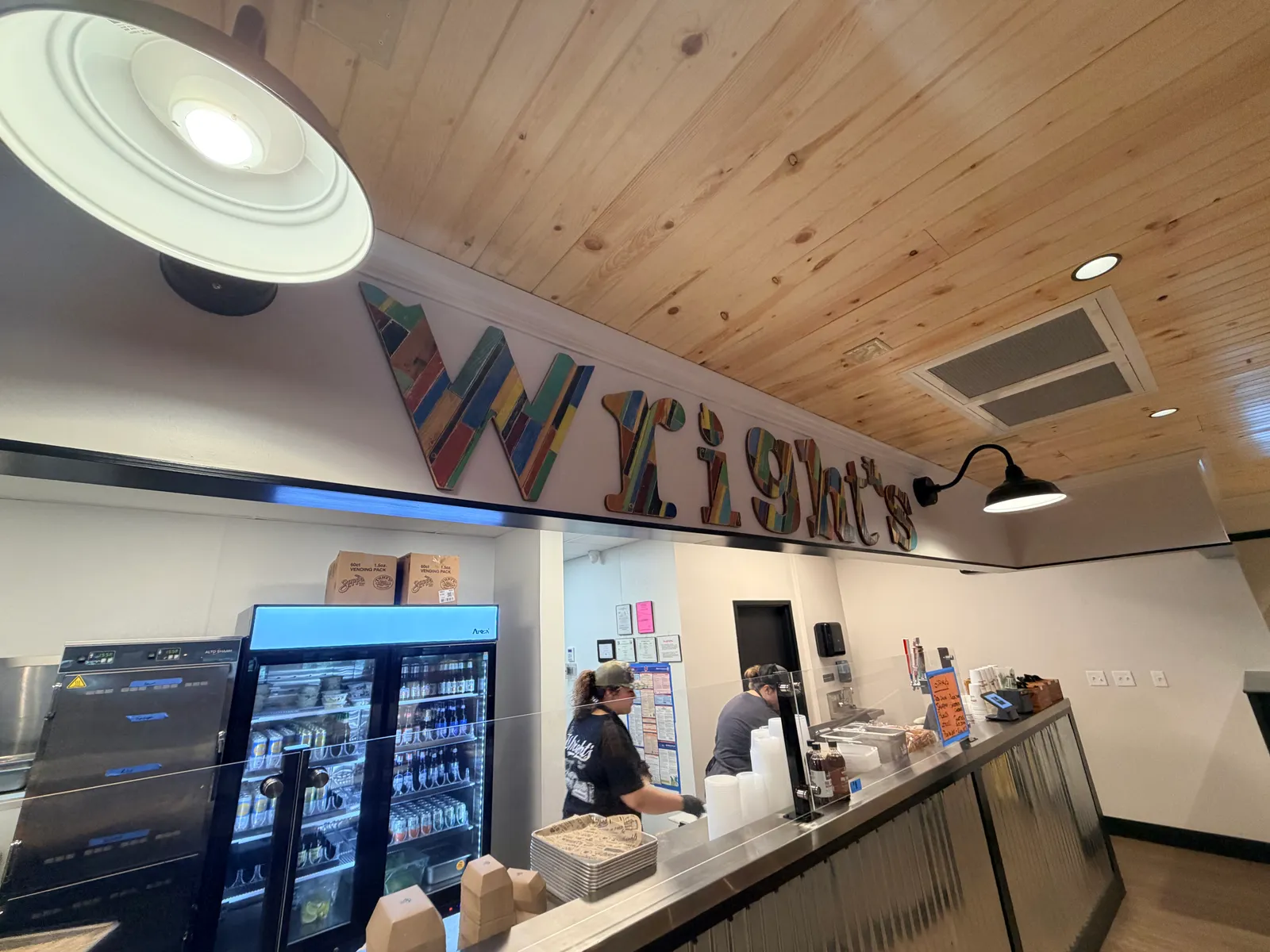 Colorful reclaimed-wood Wright's letters mounted above the counter under the pine ceiling in Benton