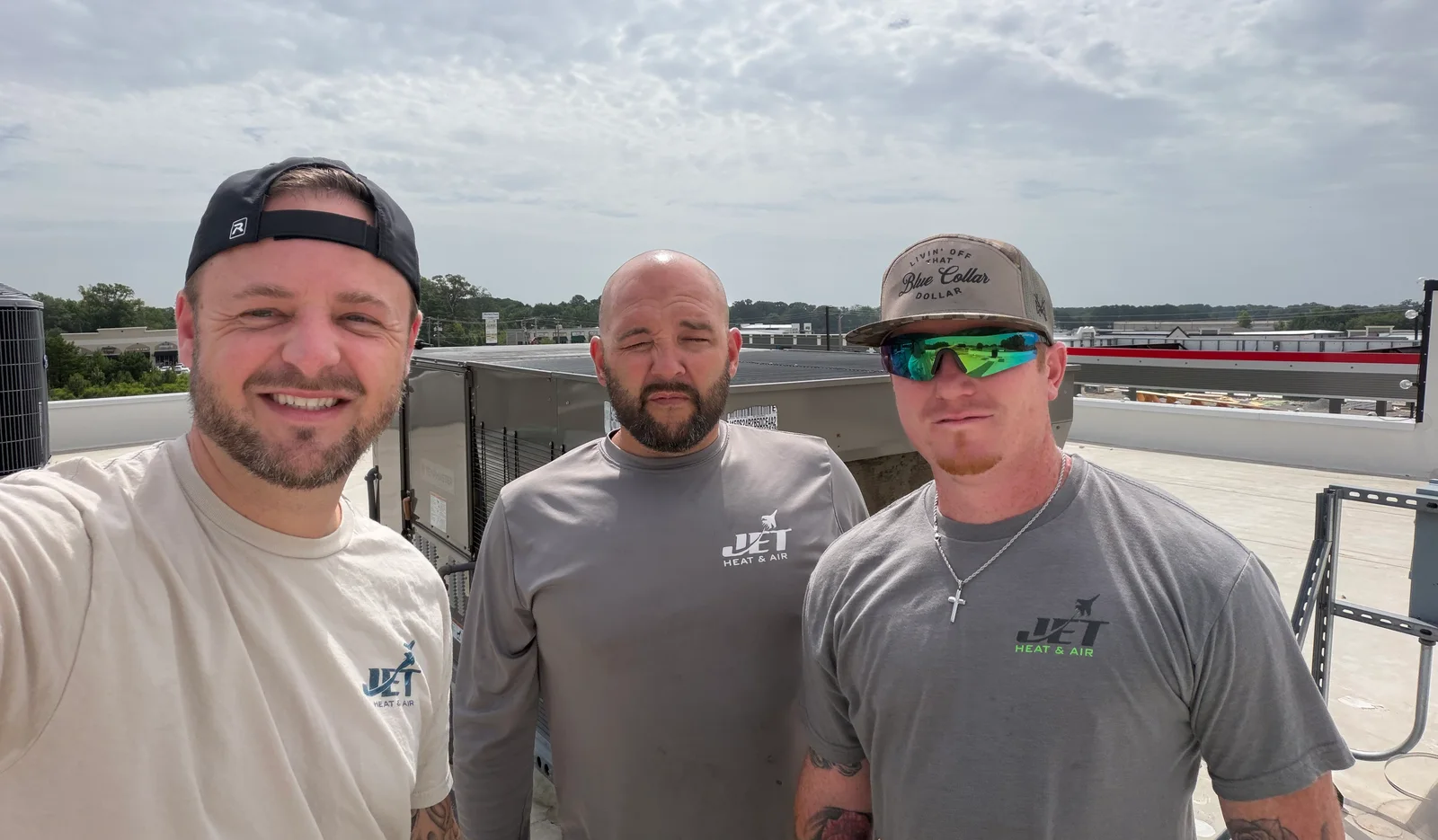 The Jet Heat and Air crew on a rooftop in Bryant, Arkansas, with the Bryant water tower behind them