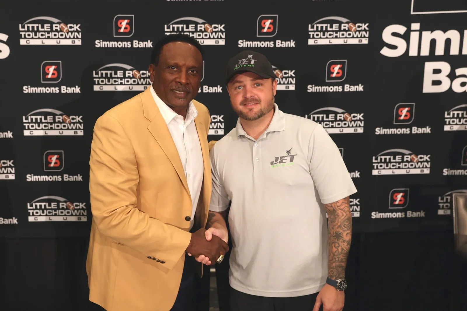 Brison McPhail of Jet Heat and Air shaking hands with NFL Hall of Famer Tim Brown in his gold Hall of Fame jacket at the Little Rock Touchdown Club