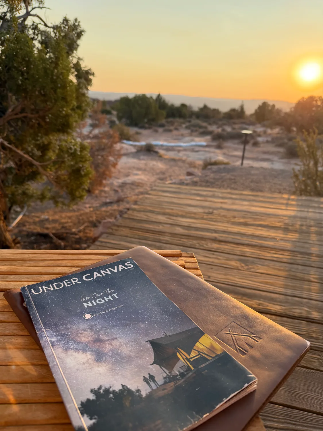 Under Canvas 'We Own The Night' magazine on a wooden bench at sunset