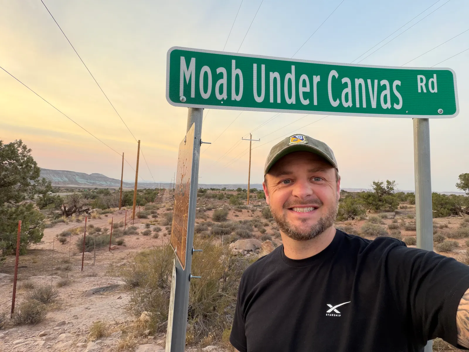 Selfie at the green Moab Under Canvas Rd street sign at dusk