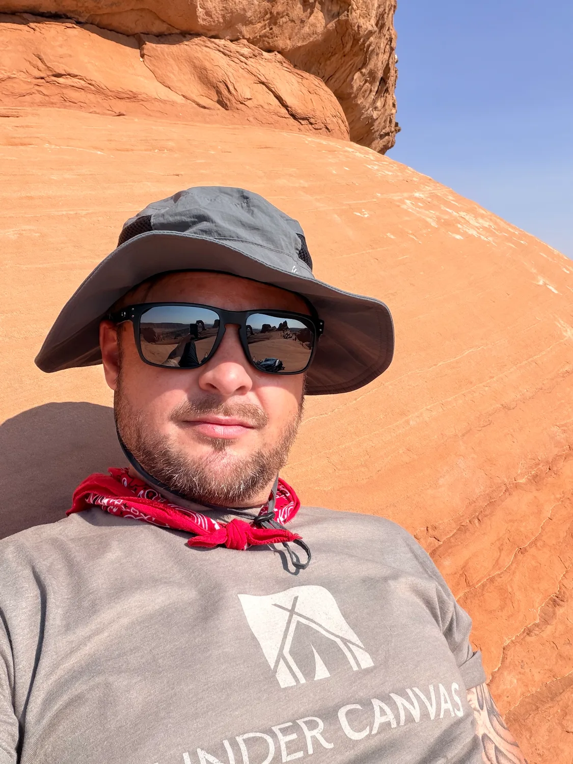 Selfie in an Under Canvas shirt with Delicate Arch reflected in sunglasses